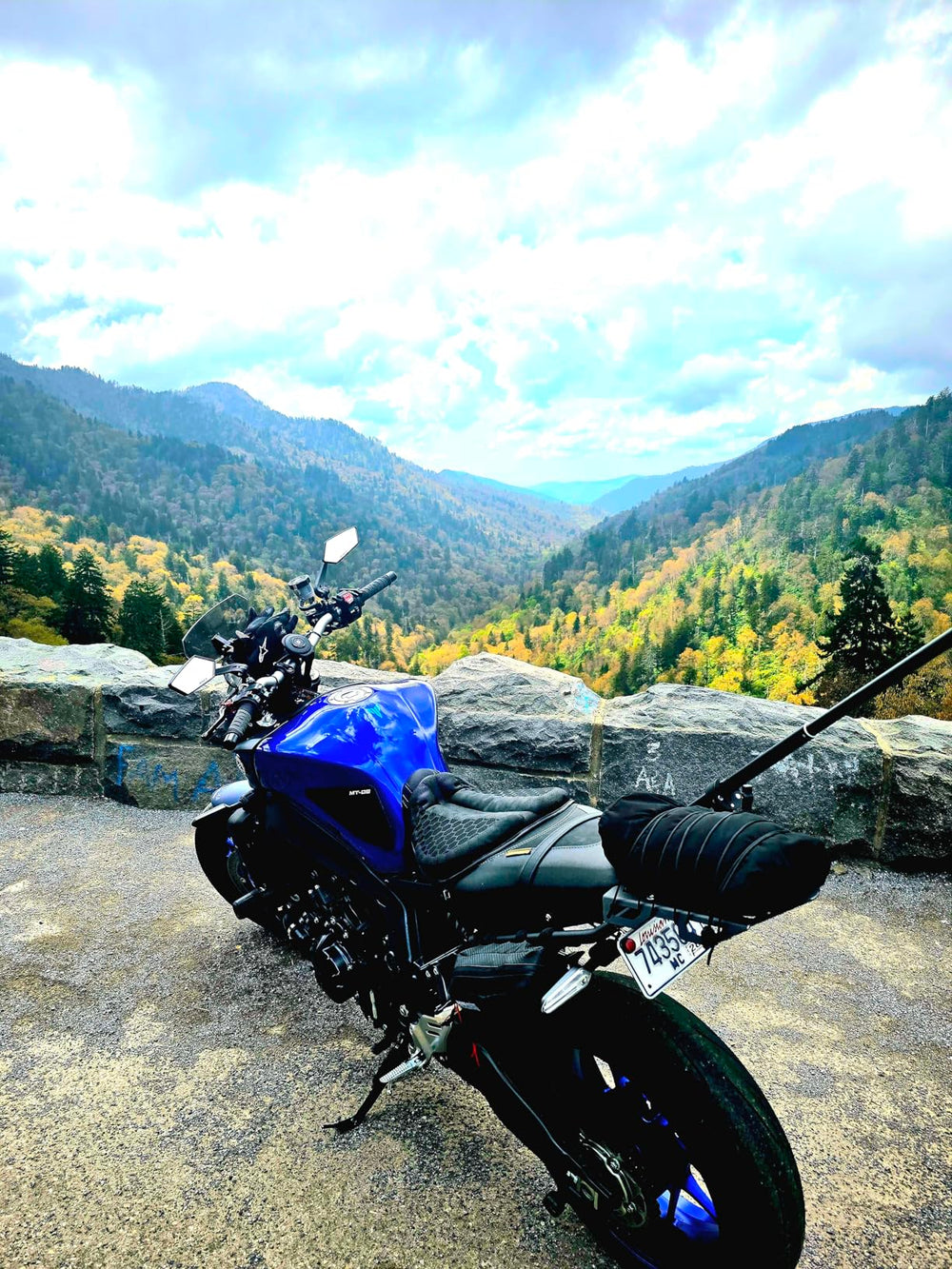 Blue motorcycle parked at a mountain overlook during a scenic ride